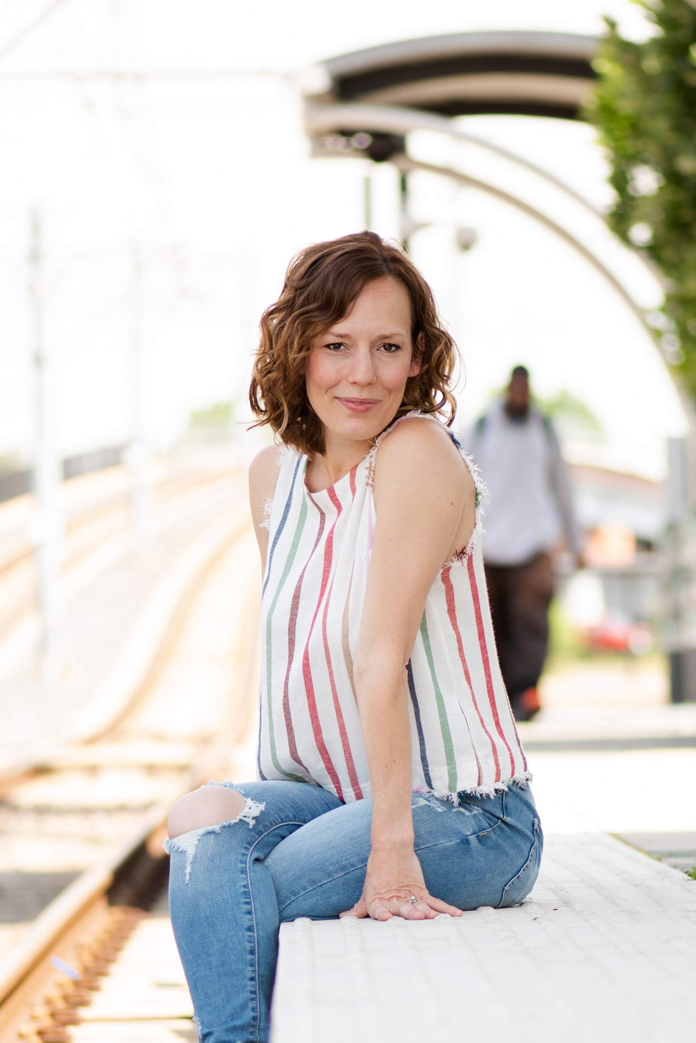 Woman poses for a picture at a light rail station.