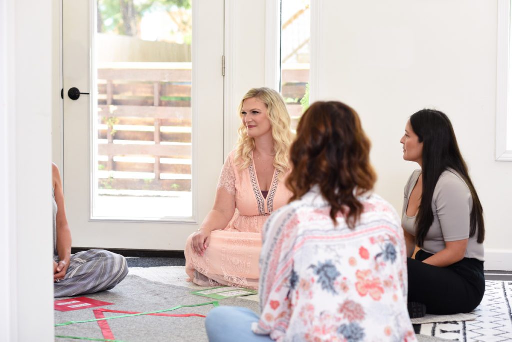 Women pose on the floor for a photo shoot of a group holistic therapy session. 